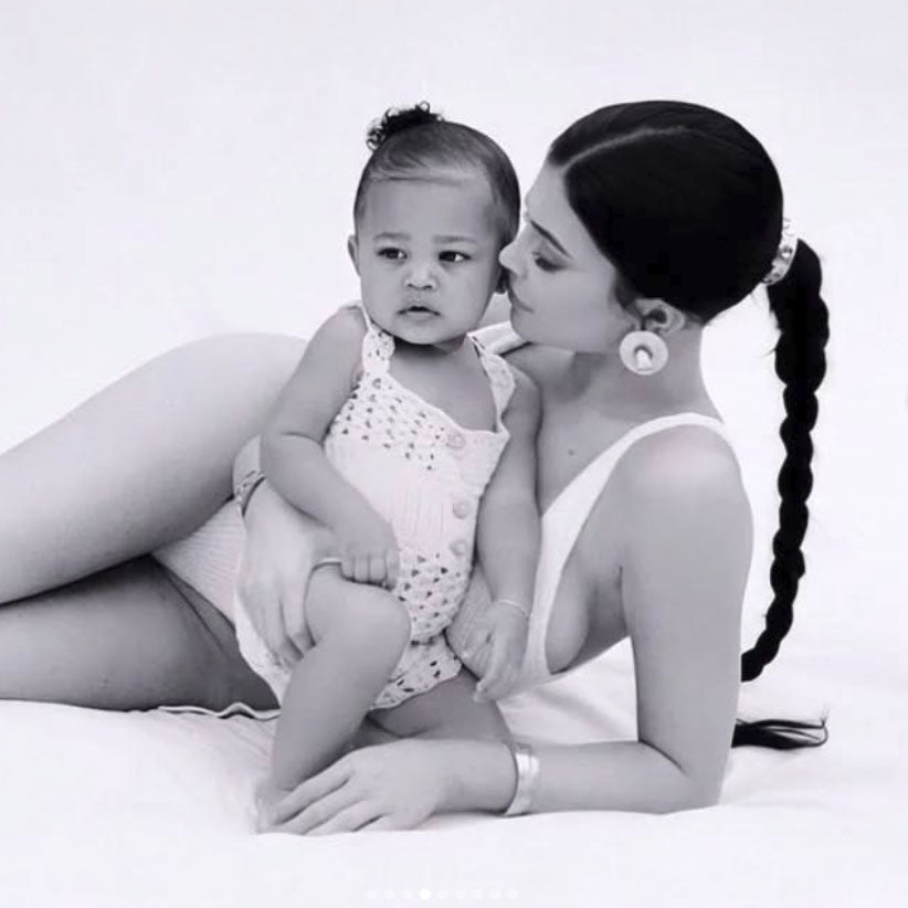 Kylie Jenner wearing earrings by STVDIO Brooklyn while posing with her child