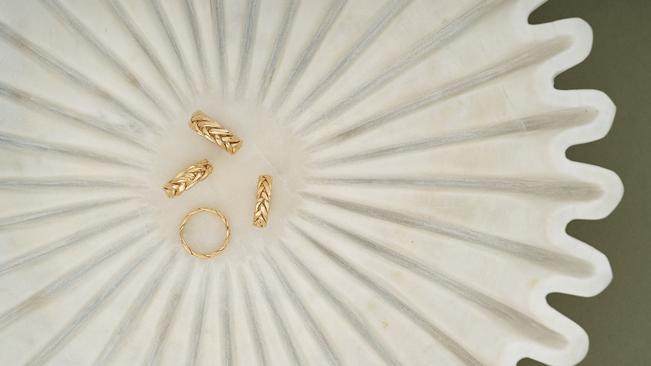 Four gold braided bands in a scalloped stone dish