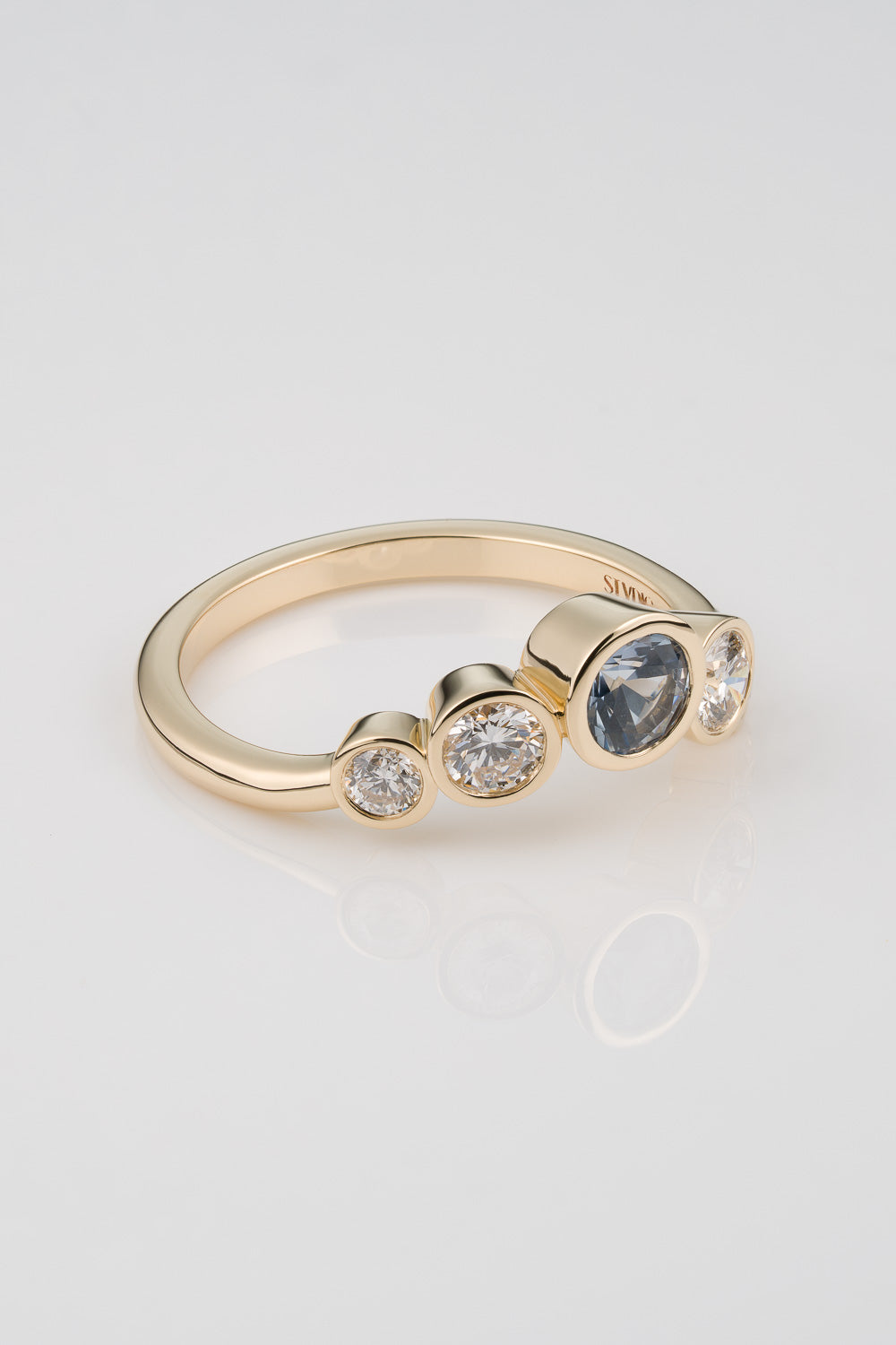 Light Blue Sapphire centerstone ring with graudated diamond detail cascading down the sides in an assymetrical layout.
