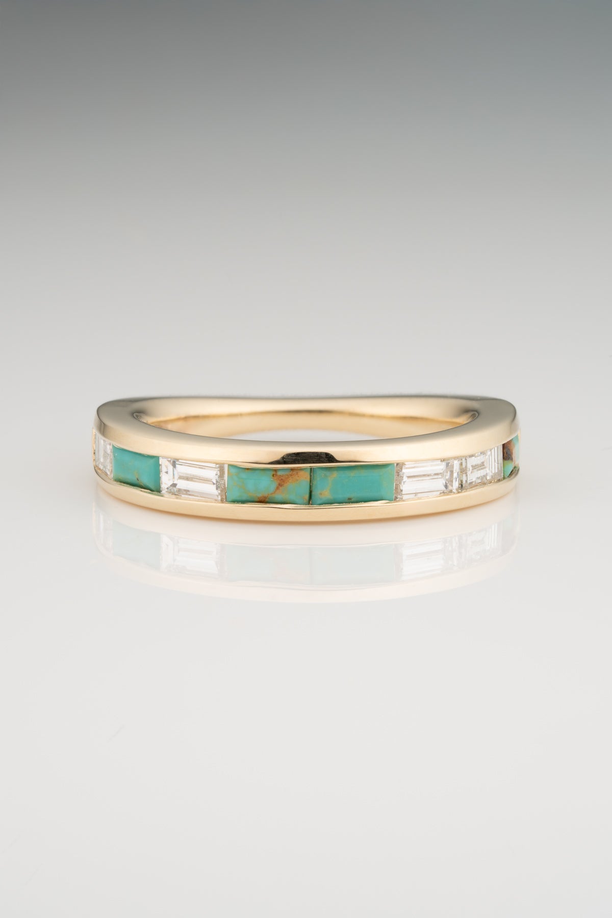 A tapered gold band inlaid with baguette-cut turquoise and white diamonds