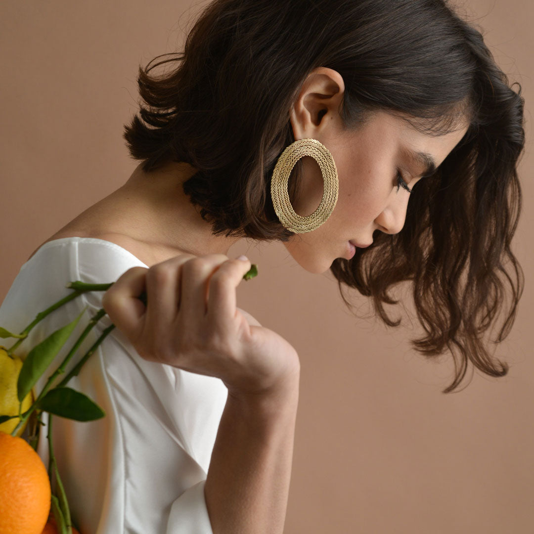 A woman wearing large, hoop, braided earrings
