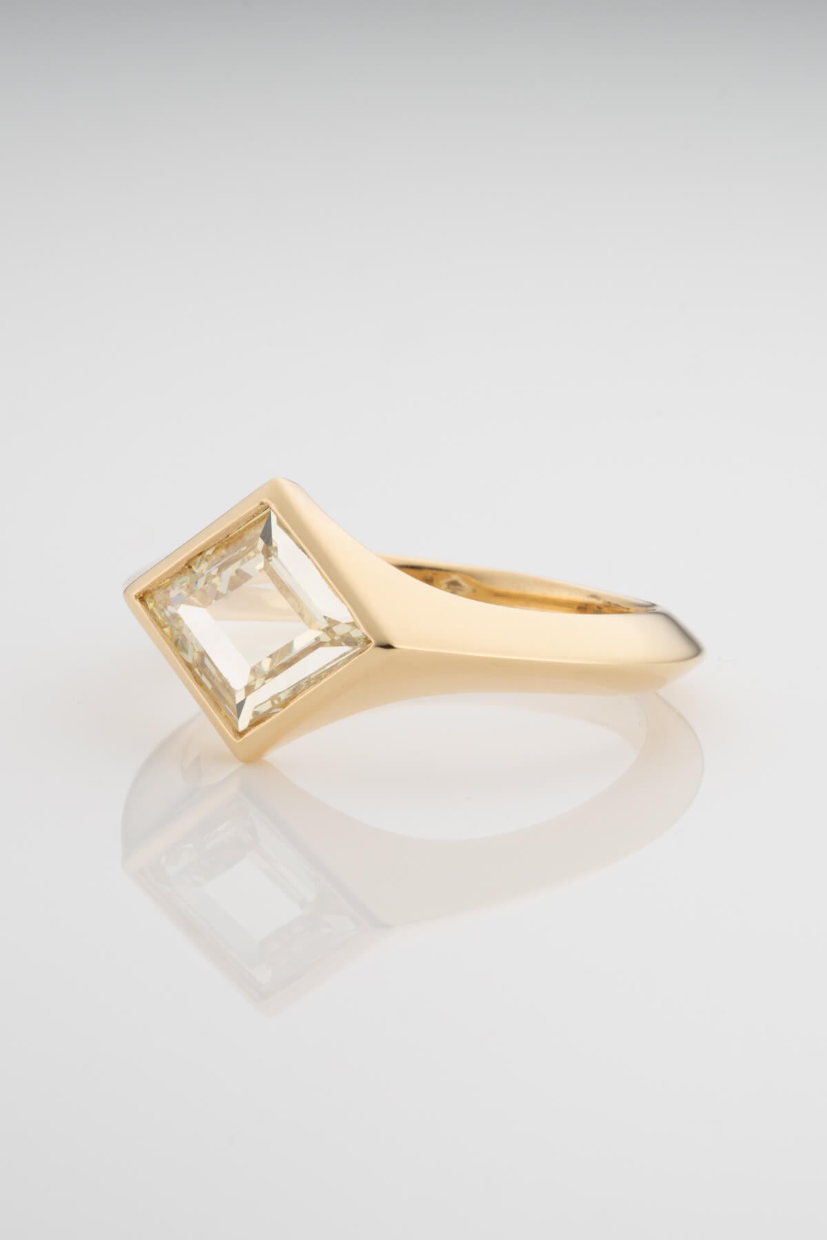 A lozenge-cut white diamond in a gold band with a graduated knife edge silhouette