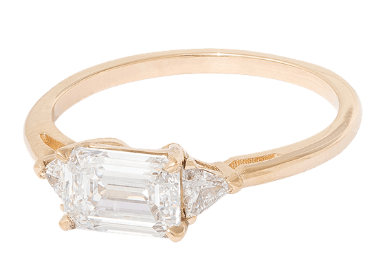 A ring featuring a large emerald-cut white diamond with two trillion-cut white diamonds on either side
