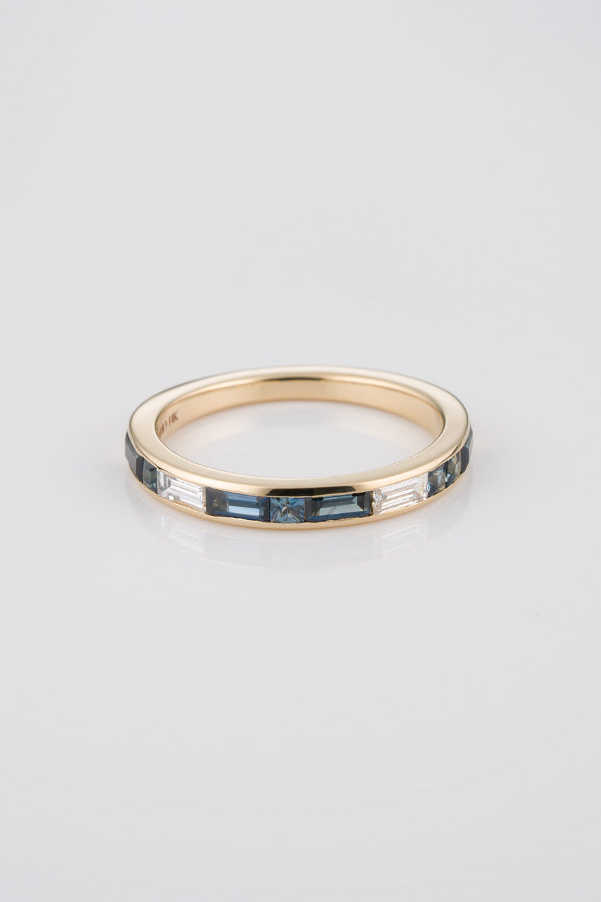 14k Gold Ring with Blue Diamond Baguettes, Princess Cuts, and White Diamonds on Neutral Background
