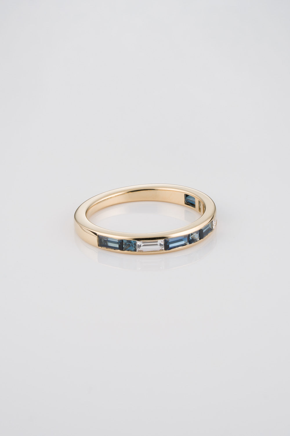 14k Gold Ring with Blue Diamond Baguettes, Princess Cuts, and White Diamonds on Neutral Background