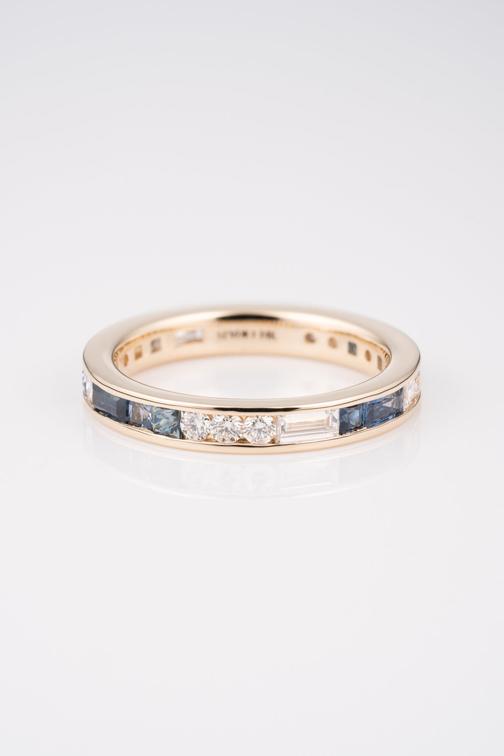 Gold Channel Set Ring with a mixture of white diamond baguettes and rounds, with Australian and Montana Sapphires scattered within the band. 