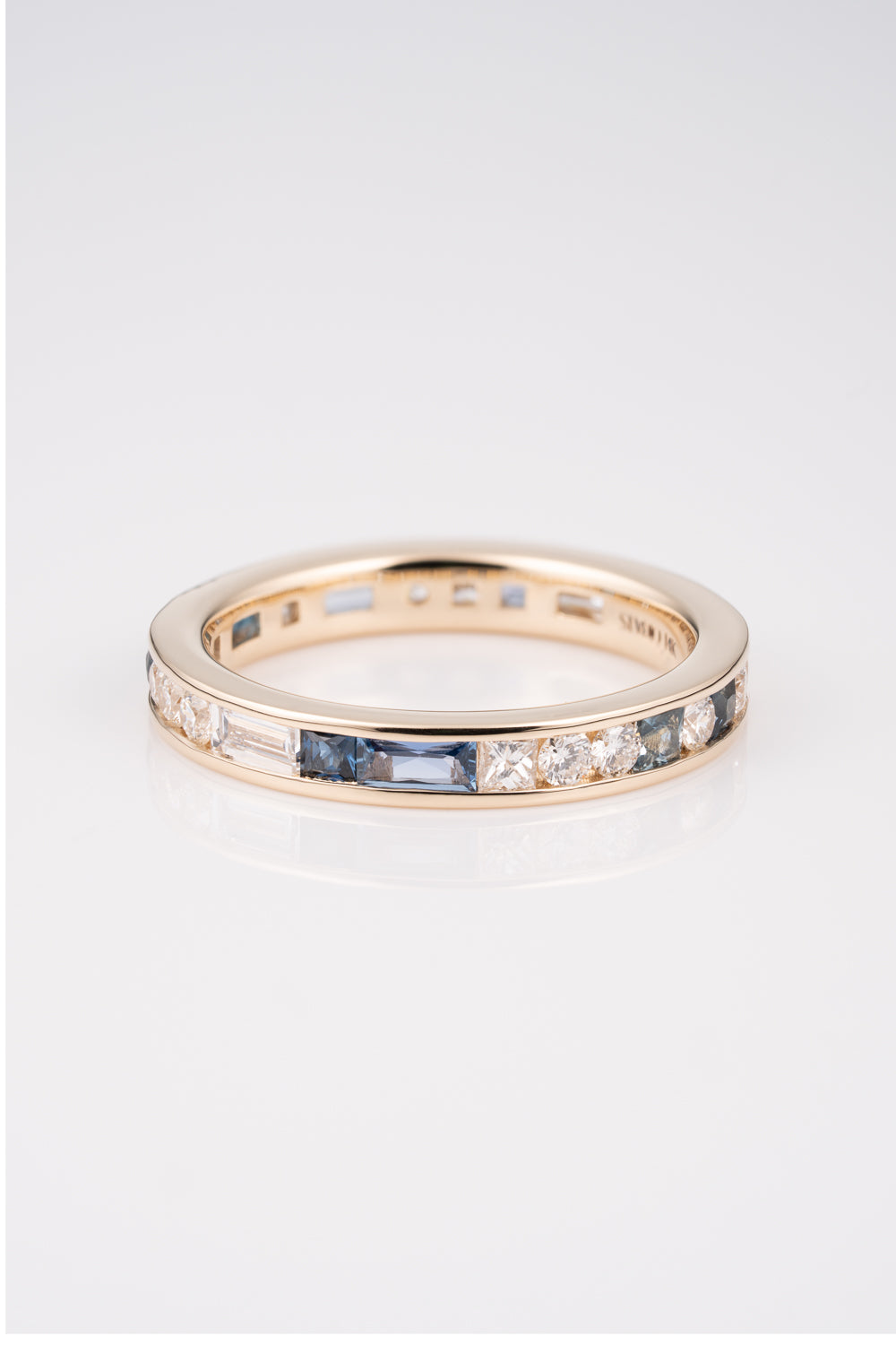 Gold Channel Set Ring with a mixture of white diamond baguettes and rounds, with Australian and Montana Sapphires scattered within the band. 