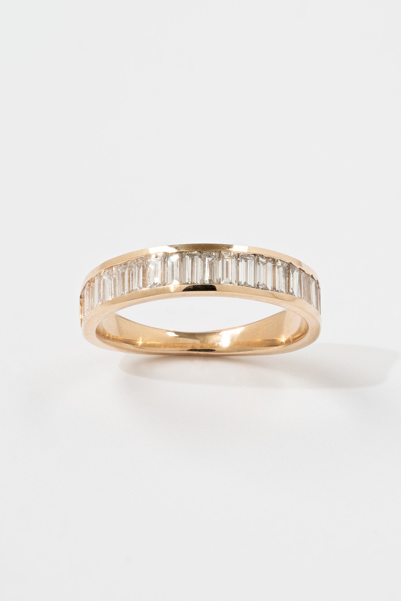A Channel Set Half Eternity Baguette Diamond Band with a Tapered Gold Backing. 