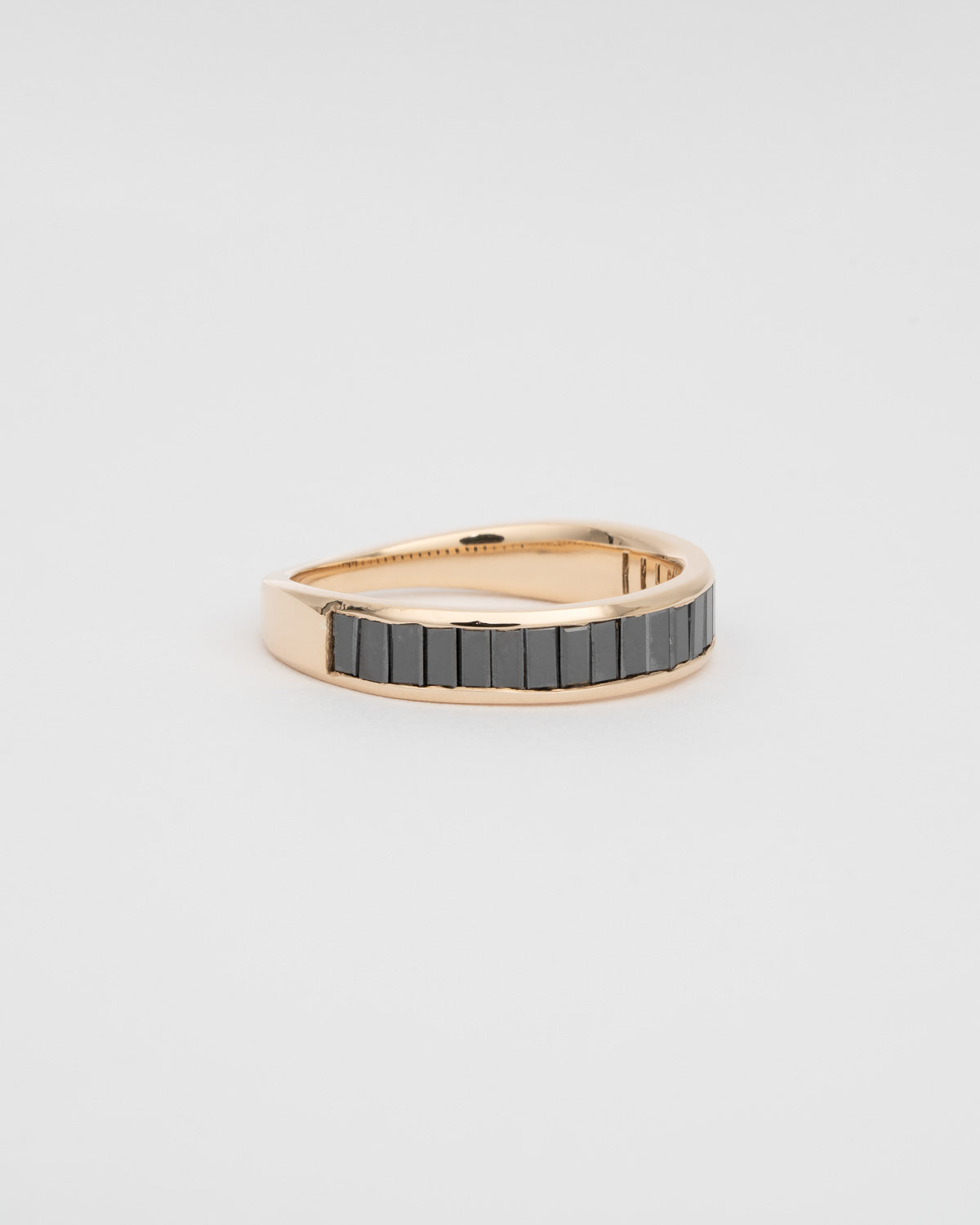 A half eternity ring with channel set black diamond baguettes and a gold tapered backing. 